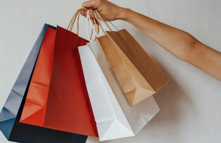Hand holding colorful shopping bags against a white background
