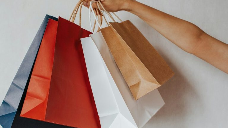 Hand holding colorful shopping bags against a white background
